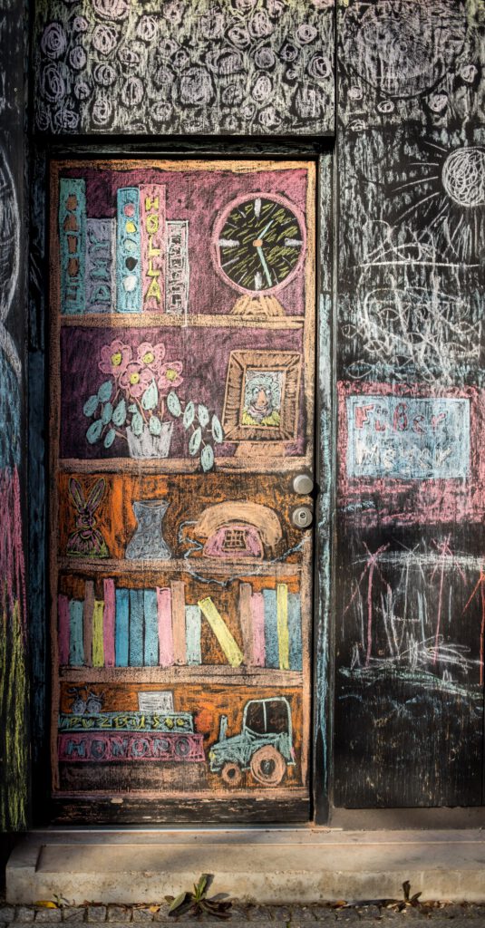 Foto von einem mit Kreide an die Wand gemaltem Regal, in welchem eine Pflanze, ein Bild, ein Telefon und Bücher stehen